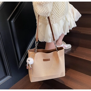 Gros plan d'un sac cabas en tricot beige avec bandoulière en cuir et peluche mignonne