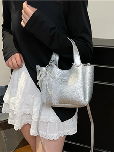 Silver wrinkled leather bucket bag with pearl lace bow on a model's shoulder