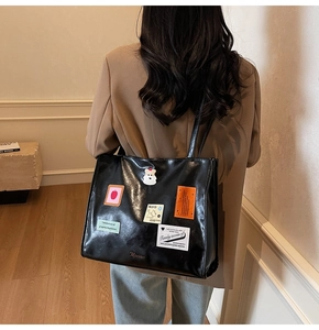 Detailed shot of a black PU leather tote bag with creative colorful patches on a model