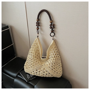 Close-up of beige woven tote bag featuring hollow crochet pattern and brown wooden bead strap