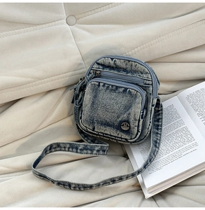 Détail du sac à bandoulière en denim délavé avec logo M FASHION et double fermeture éclair