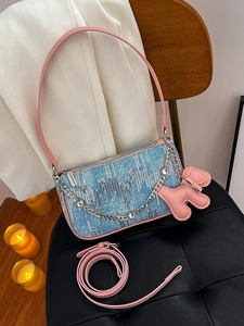 Sequin denim underarm bag with pink leather strap and rhinestone chain in a cozy setting