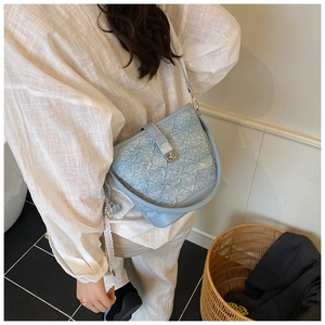 Dettaglio borsa a secchiello in denim azzurro con chiusura a scatto e ciondolo in pizzo