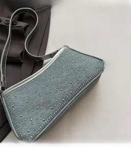 Dettaglio della borsa a spalla in denim grigio-blu con borchie argentate e strass