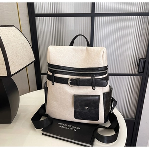 Detailed close-up of cream tweed backpack with black leather straps on a modern table
