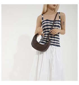Detailed view of deep brown crescent bag with stitching on striped knit outfit