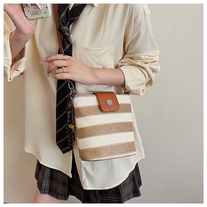 Détail du sac seau tissé à rayures avec rabat en cuir et foulard à carreaux élégant