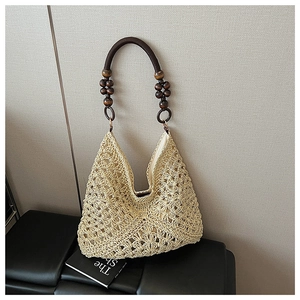 Detailed view of hollow woven texture and wooden bead handle on the straw tote bag