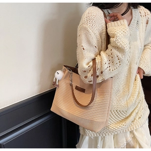 Détail du sac fourre-tout en tricot beige avec anses en cuir et breloque en peluche