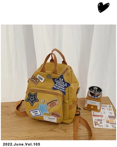 Detailansicht eines gelben Vintage-Canvas-Rucksacks mit Stickereien und Tragegriff aus Gurtband