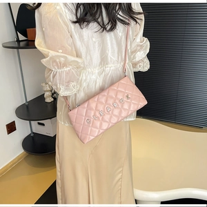 Detail of pink quilted shoulder bag with silver CLEARK metal letters on model