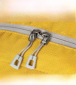 Detail of durable two-way metal zippers on yellow ripstop fabric for hiking backpack