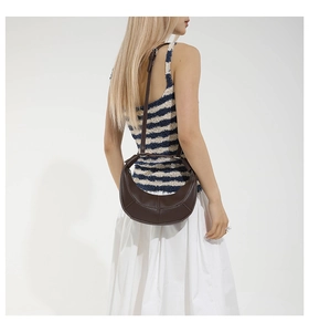 Detailed view of brown litchi grain leather crescent bag with adjustable strap and stitching