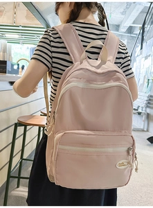 Pink waterproof nylon backpack with multiple zipper compartments and brand logo patch