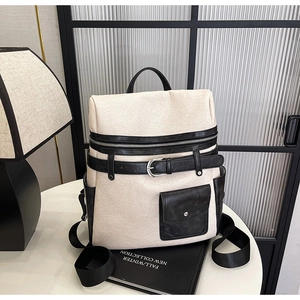 Detail of cream canvas backpack with black faux leather straps and silver buckle closure
