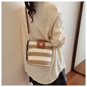 Détail du sac seau tissé rayé avec bandoulière en cuir marron porté par le modèle