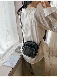 Détail du sac bandoulière en denim avec logo métallique et bandoulière ajustable