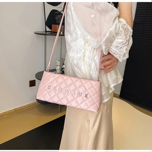 Close-up of pink quilted faux leather shoulder bag with silver metal letter buckle