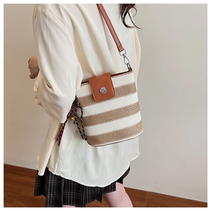 Détail du sac seau tissé à la main avec rabat en cuir marron et fermoir rotatif en métal