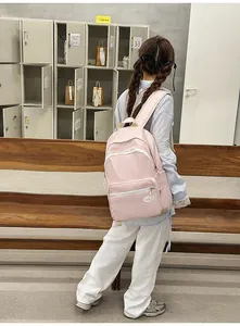 Detailed view of a light pink casual backpack with front pocket used in a school setting