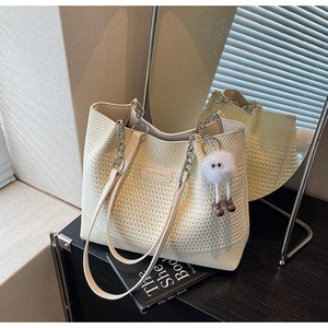 Détail du sac tricoté crème avec logo en métal, chaîne argentée et pompon peluche