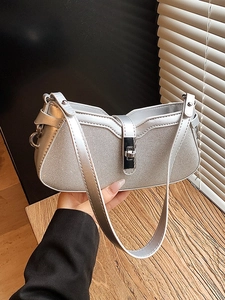 Silver metallic shoulder bag with grid texture and flip-lock shown in artistic light