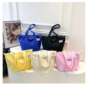 Detail view of large canvas tote bags in five vibrant colors with stylish metal buckle straps