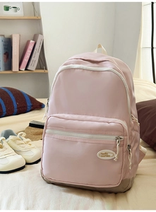 Detail of pink nylon backpack with grey base reinforcement in a cozy bedroom setting