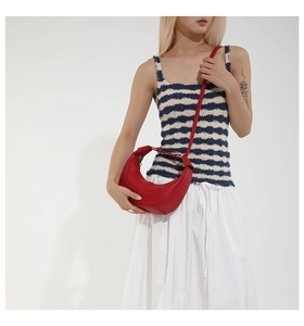 Detail of red crescent leather bag with visible stitching and adjustable shoulder strap