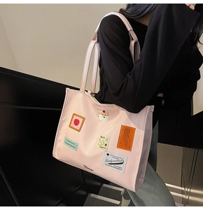 Detail of light pink large capacity tote bag with decorative patches and shoulder straps