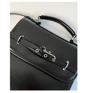 Close-up of shiny black leather backpack with silver metal rings and hooks detail