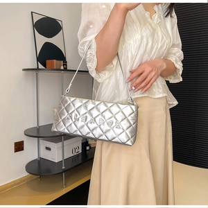 Close-up of silver quilted shoulder bag featuring metal CLEAR OK lettering detail