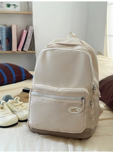 Detail of minimalist cream nylon backpack with hello DAPING logo and brown base panel