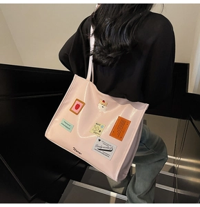 Close-up of pink patent leather tote bag with cartoon patches on a modern staircase