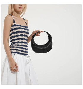 Detail of minimalist black crescent handbag featuring refined curved stitching and premium leather