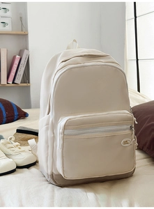 Detail view of beige casual backpack with multiple zipper pockets and reinforced bottom base
