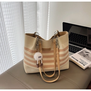 Détail du sac cabas en tricot à rayures oranges avec étiquette en cuir et grigri peluche