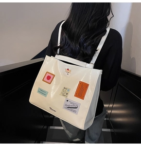 Detail of white patent leather tote bag with cartoon patches and Noro logo on staircase