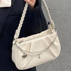 Sac nuage plissé chic en crème avec bandoulière tressée et breloques cœur sur un modèle