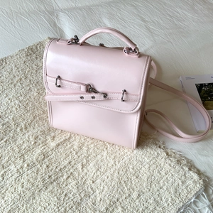 Detail of light pink faux leather bag with silver buckle on textured carpet background