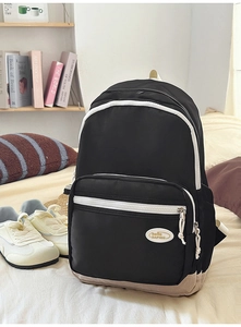 Detail of casual backpack featuring a black nylon body with reinforced beige bottom panel