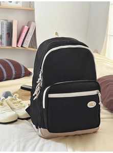Detail of minimalist black backpack featuring contrasting white zippers and woven pull cords