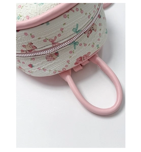 Detail of cartoon bunny pattern on white textured fabric with pink handle and zipper