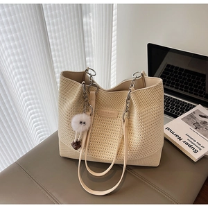 Détail d'un sac cabas en maille beige avec texture 3D et étiquette de marque en cuir