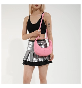 Pink half-moon leather crossbody bag with geometric stitching shown on a model