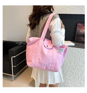 Detail view of pink canvas tote bag with fashion label and button pocket on back