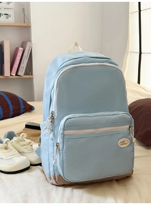 Detail of light blue nylon backpack with khaki contrast bottom and white zippers