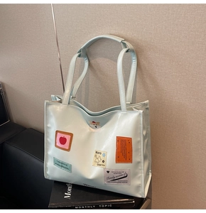 Close-up of mint green tote bag with embroidered cartoon dog and apple patches
