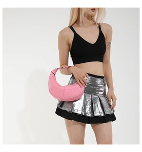 Pink crescent shoulder bag with geometric stitching shown on model in a minimal setting