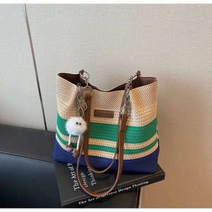 Détail du sac de plage en tricot avec rayures, brides en cuir et breloque en peluche